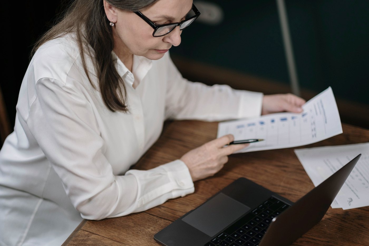 Profesional analizando reportes financieros junto a su laptop